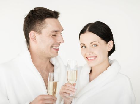 healthcare and beauty concept - picture of couple in spa salon in white bathrobes with champagne