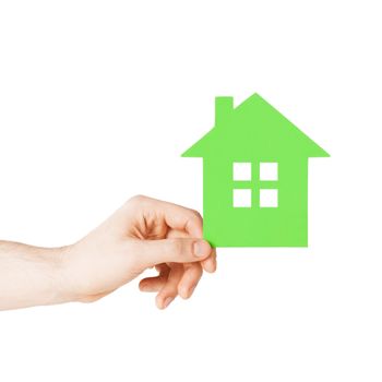 real estate and family home concept - closeup picture of male hand holding green paper house