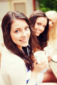 holidays and tourism concept - beautiful girls drinking coffee in cafe