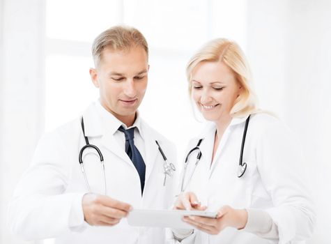 healthcare and technology concept - two doctors looking at tablet pc