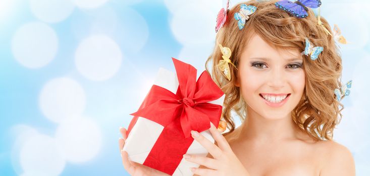 health, holidays and beauty concept - happy teenage girl with butterflies in hair showing gift box