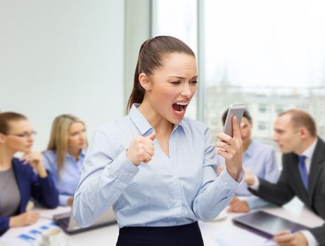 business, technology and education concept - screaming businesswoman with smartphone in office