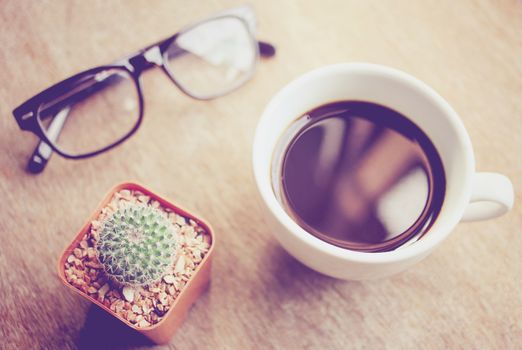 Black coffee and eyeglasses with cactus, retro filter effect