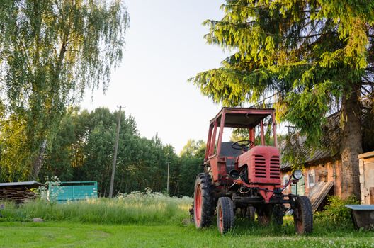 village view farm red old tractor in meadow summer time