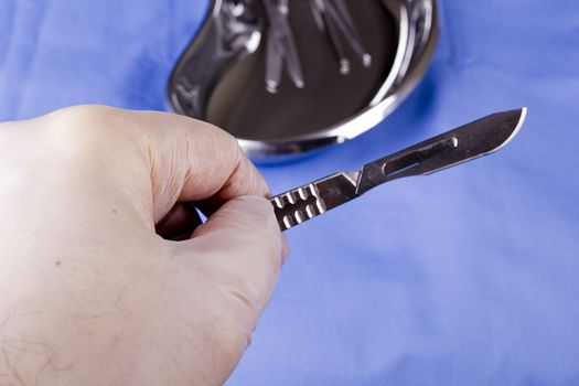 Surgical scalpel in hand with a latex glove.