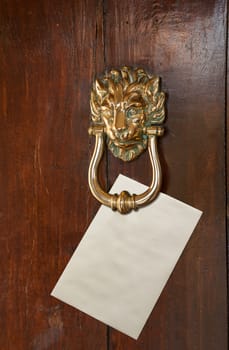 Envelope with space for text placed under a brass lion head door knocker on old oak door