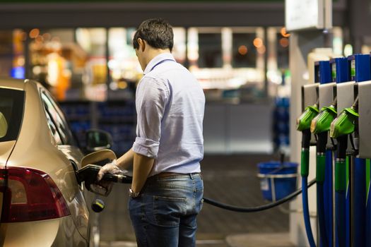 Young man fueling his car at the gas station