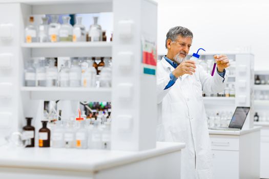 Senior male researcher carrying out scientific research in a lab (shallow DOF; color toned image)