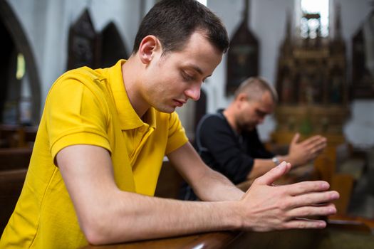 Handsome young man praying in a church