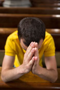 Handsome young man praying in a church