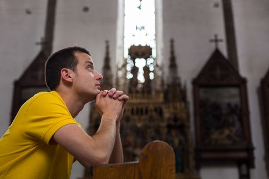 Handsome young man praying in a church