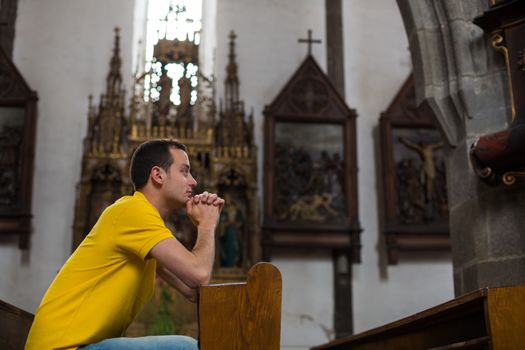 Handsome young man praying in a church