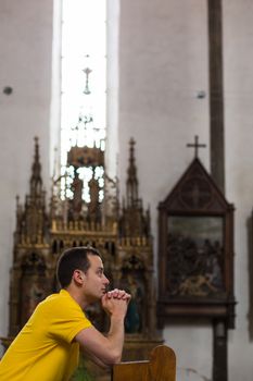 Handsome young man praying in a church