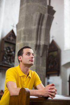 Handsome young man praying in a church