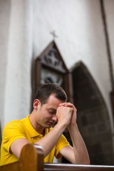 Handsome young man praying in a church