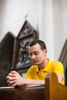 Handsome young man praying in a church