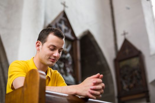 Handsome young man praying in a church