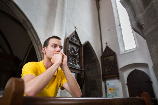 Handsome young man praying in a church