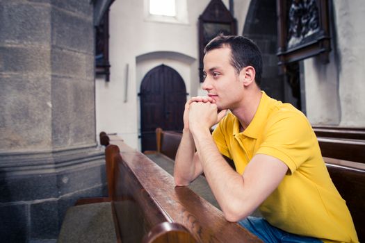 Handsome young man praying in a church