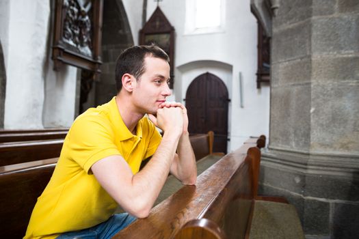 Handsome young man praying in a church