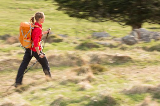 Pretty, young woman hiking in mountains (motion blurred image)