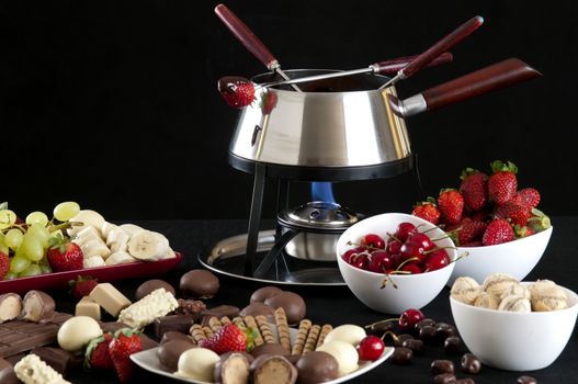 Fondue melted chocolate dip with different flavors on black background