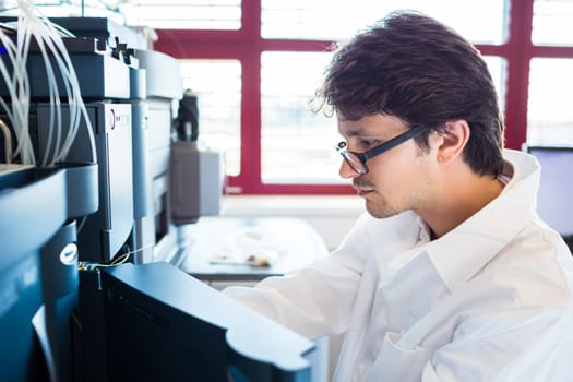 Male researcher carrying out scientific research in a lab (shallow DOF; color toned image)