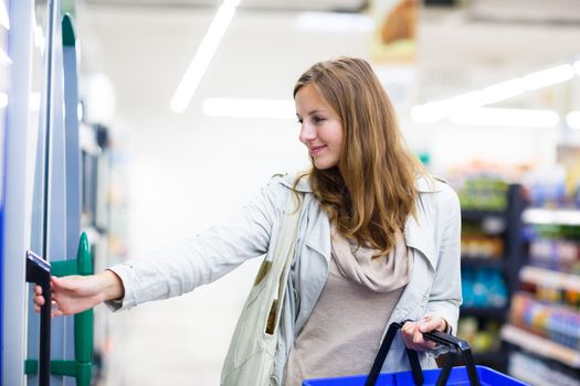 Beautiful young woman shopping in a grocery store/supermarket (color toned image)