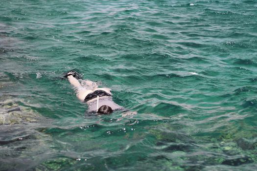 Woman photographer diving into water of Red sea