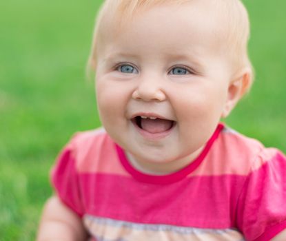 portrait of a smiling baby on a green lawn