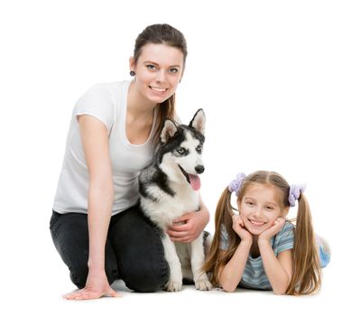 two smiling sisters and a husky dog sitting on the floor on a white background