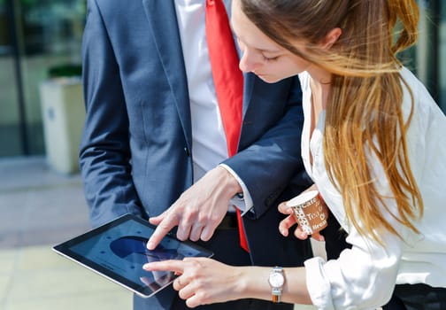 Junior executives consulting a touchpad in front of their company