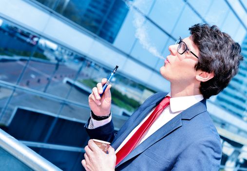 Nice portrait of young worker during coffee break with an electronic cigarette