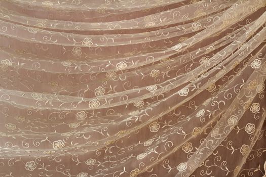 The beautiful transparent tulle decorated with an embroidery and draped in the form of folds.