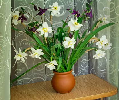 Beautiful large flowers of narcissuses in a vase on a table 