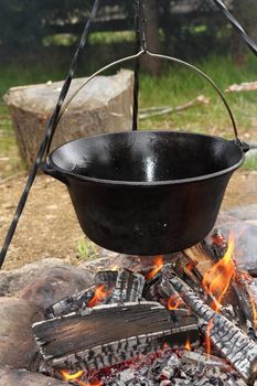healthy cooking on ancient traditional big metal pot ( vintage black cauldron ) on camp fire