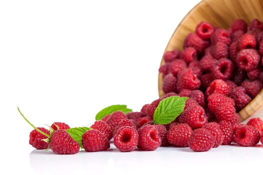 Fresh raspberries with leaves in wooden bowl on white background