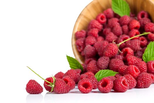 Raspberries with leaves in wooden bowl on white background