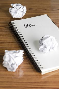 notebook write idea word with crumpled on wooden background