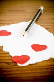 white paper with pencil and red heart on wooden background concept for valentine day