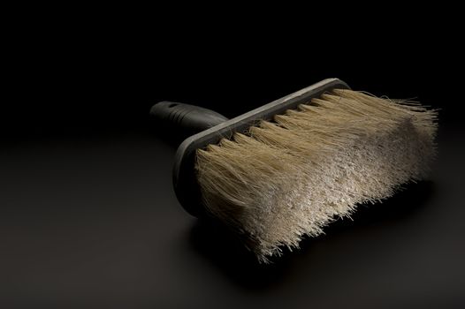 Close up view of a new clean large paintbrush or wallpapering brush lying on a dark background conceptual of DIY, home renovations, building and construction or interior decoration