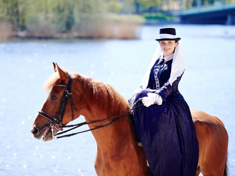 Lady on a  horse. The lady on riding walk. Portrait of the horsewoman. The woman astride a horse. The aristocrat on riding walk.