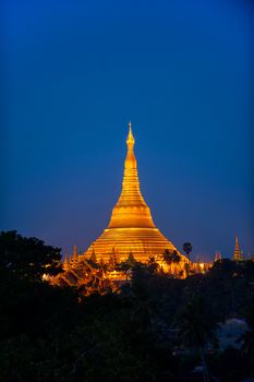 Shwedagon Pagoda Temple with village below in the twilight at Yangon, Myanmar (Burma)