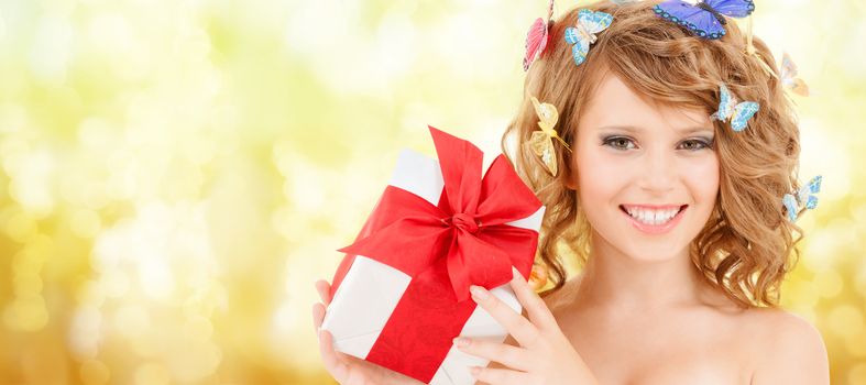 health, holidays and beauty concept - happy teenage girl with butterflies in hair showing gift box