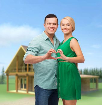 love and family concept - smiling couple showing heart with hands