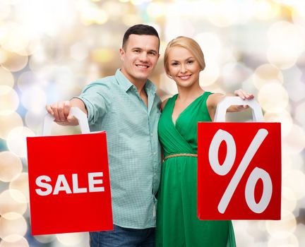 happiness, shopping and couple concept - smiling couple with shopping bags with sale and percent sign