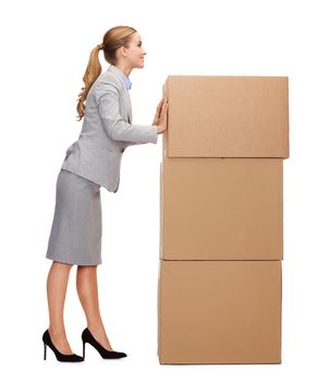 business, post and transportation concept - smiling businesswoman pushing tower of cardboards