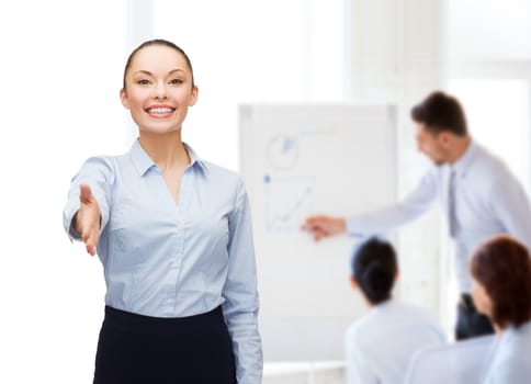 business, gesture and education concept - friendly young smiling businesswoman with opened hand ready for handshake