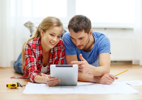 repair, building, renovation and home concept - smiling couple looking at tablet pc at home