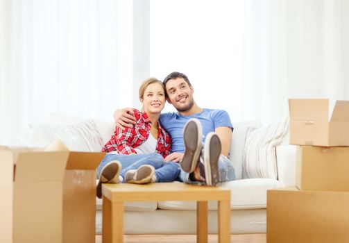 moving, home and couple concept - smiling couple relaxing on sofa in new home